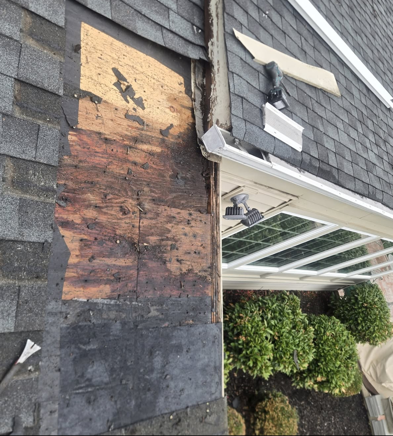 Roof tiles stripped back exposing the damaged timber deck at a leaking corner gutter during an emergency repair