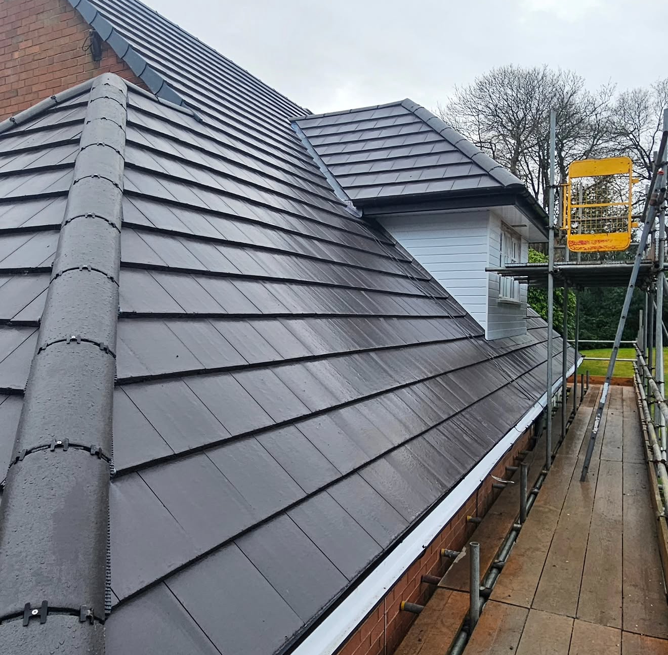 New grey concrete interlocking tiled roof with dry-fix ridge, photographed from scaffolding