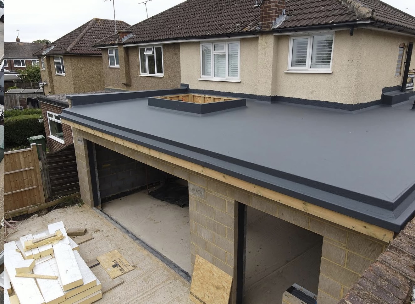 New grey single-ply flat roof on a brick garage extension with a rooflight opening