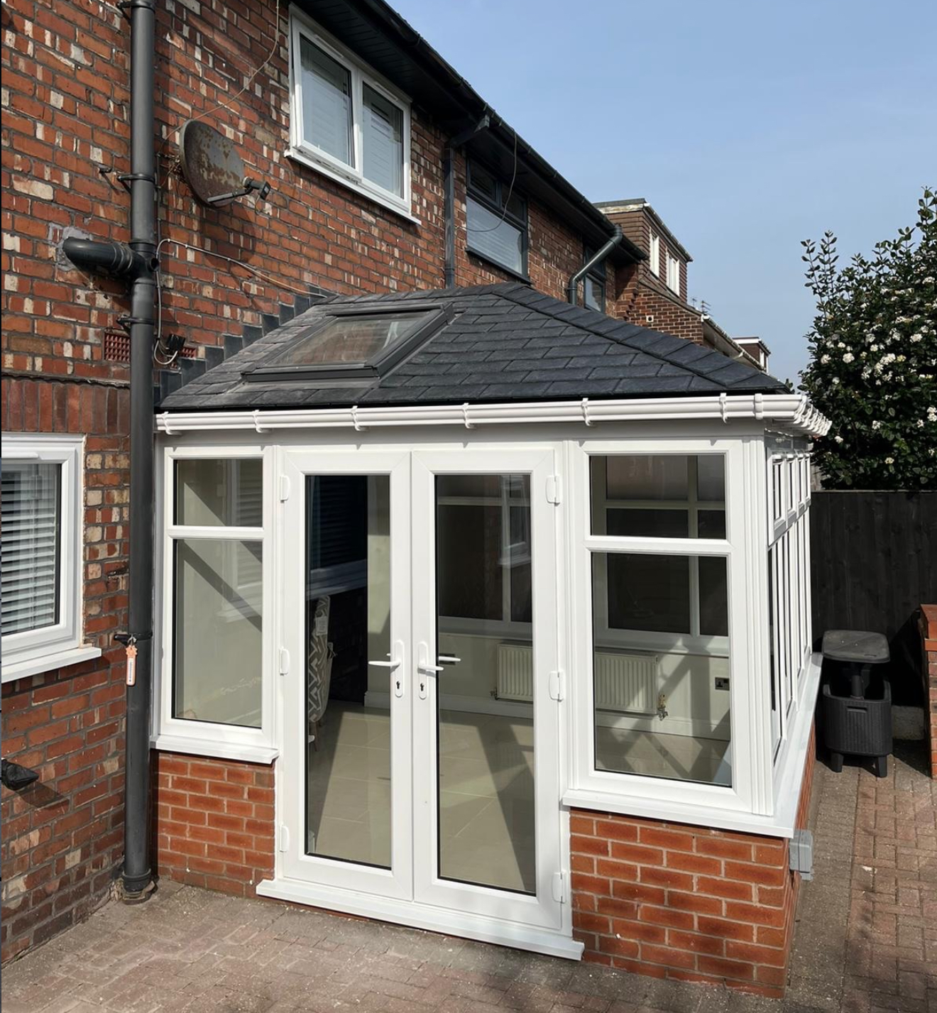 White-framed conservatory with dark slate hipped roof and rooflight
