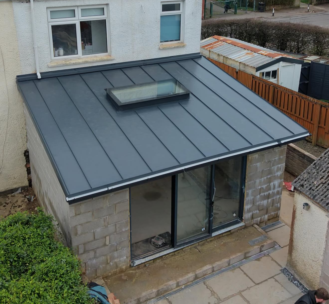 New dark standing-seam metal roof with a rooflight over a partially completed extension