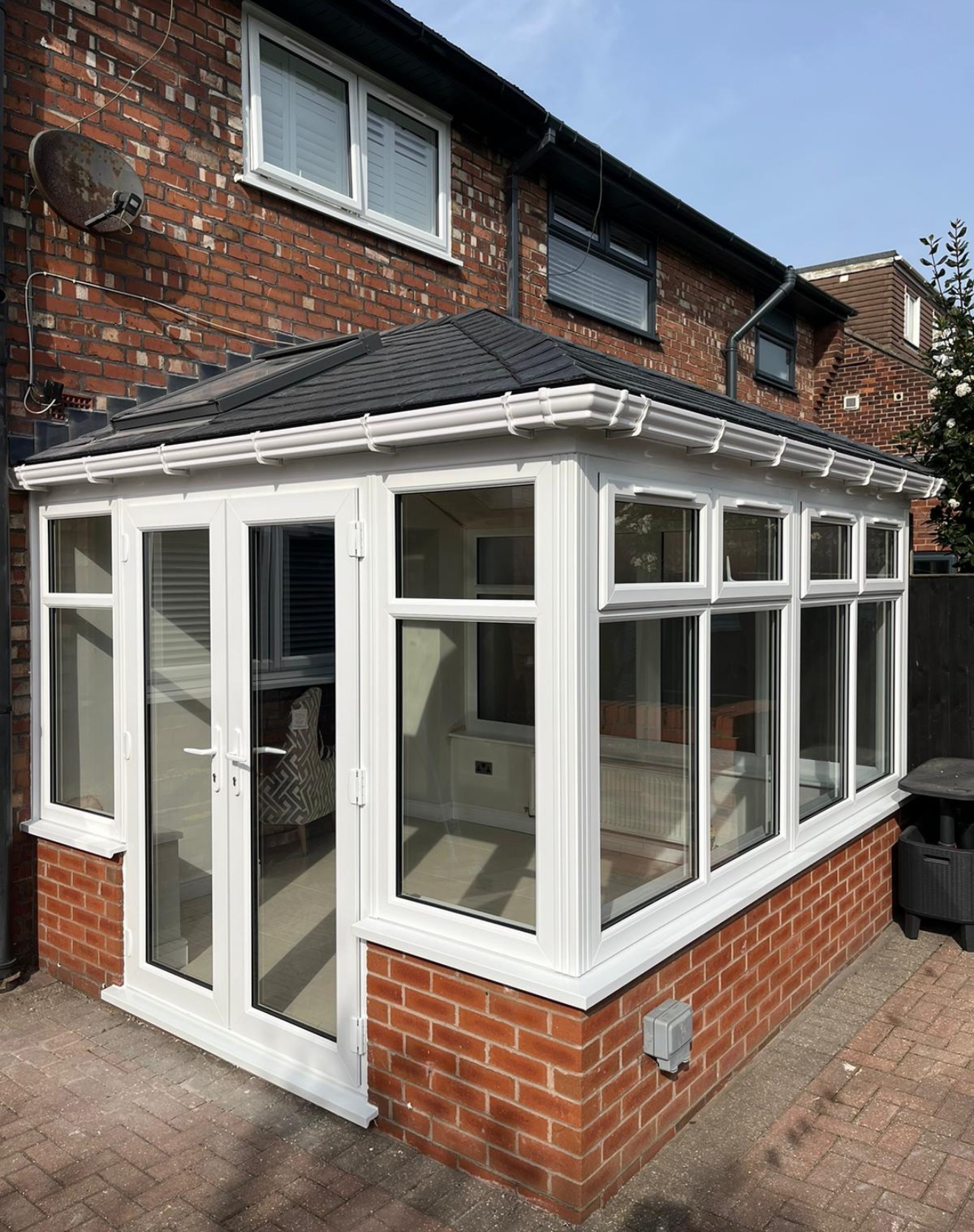 White-framed conservatory with a dark slate hipped roof and glazed sides
