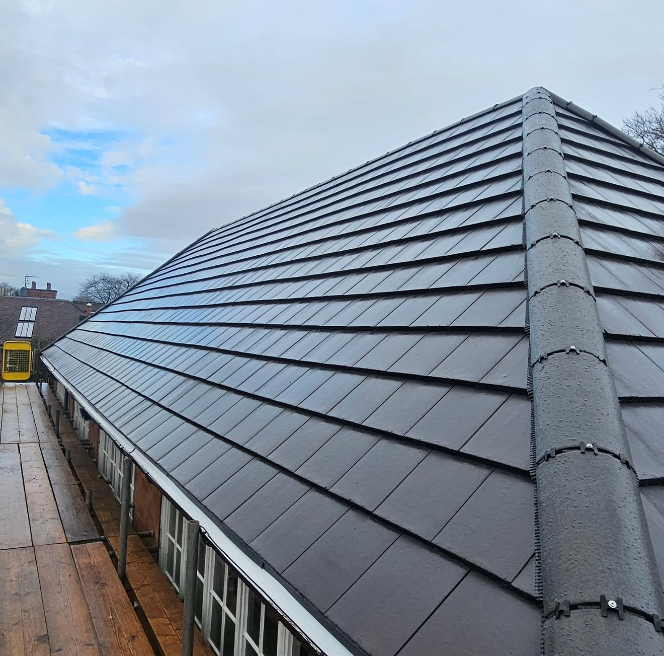 Freshly laid grey interlocking concrete tiles with white fascia and dry ridge